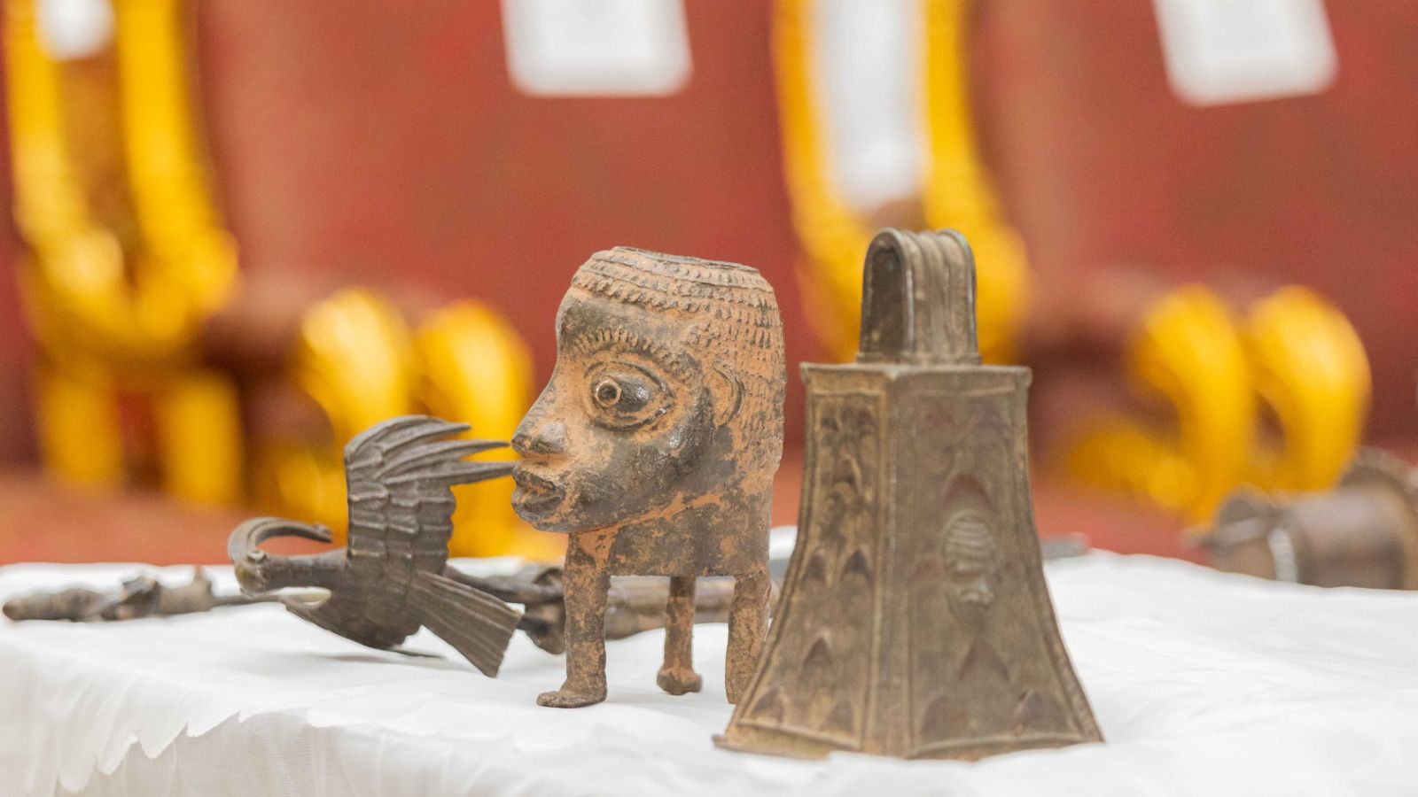 Die vier restituierten Objekte, die von Oba Ewuare II. gesegnet wurden: eine Glocke, die geläutet wurde, um die Ahnen anzurufen; ein kopfförmiger Behälter für Kräuter und Medizin, das den göttlichen Boten Ofoe darstellt, mit drei Gliedmassen, die aus seinem Kopf entwachsen, aber ohne Rumpf; ein Klangstab mit Wahrsagevogel, der die göttliche Macht des Ọba zum Schutz des Königreichs verdeutlicht; sowie ein Fragment eines Zepters, ein Insignium der Titelträger im der königlichen Palastgesellschaft von Benin.